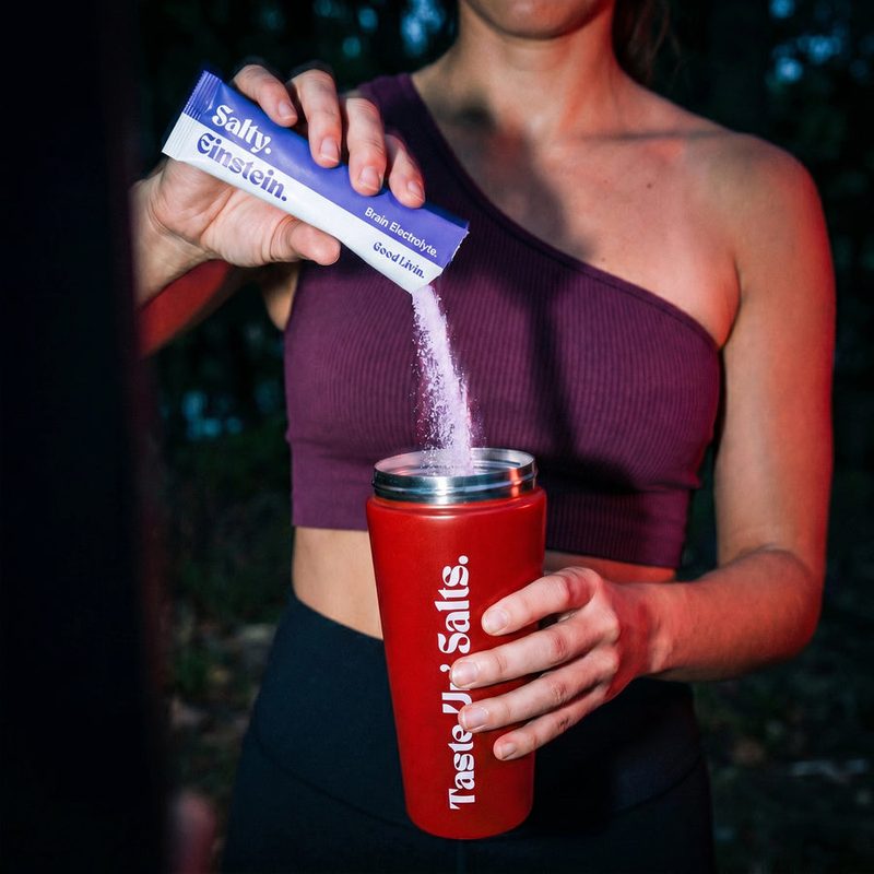 Pouring a Salty Einstein stick pack into a red insulated tumbler
